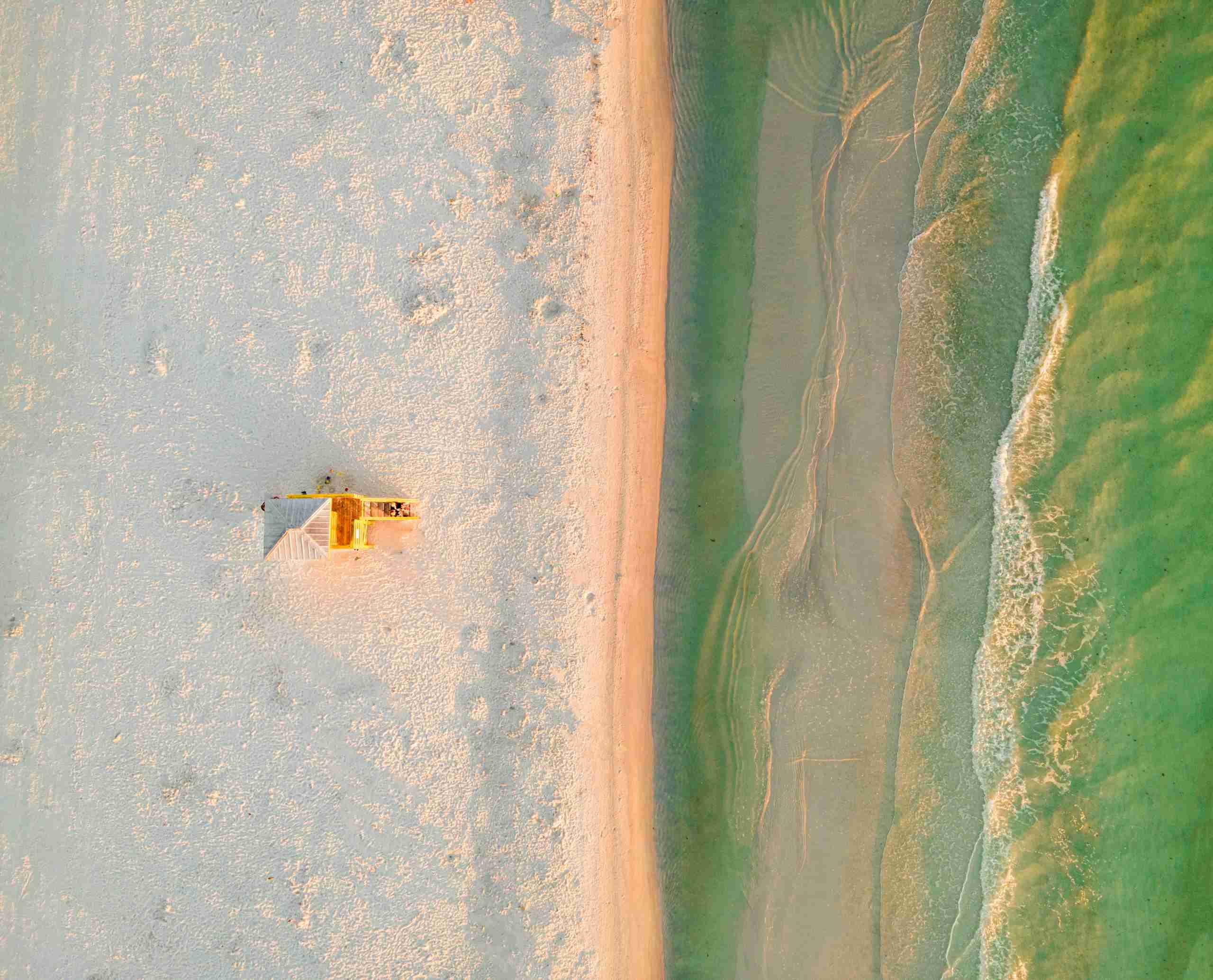 Drone shot of Siesta Key beach showcasing the lifeguard tower and tranquil turquoise waters.